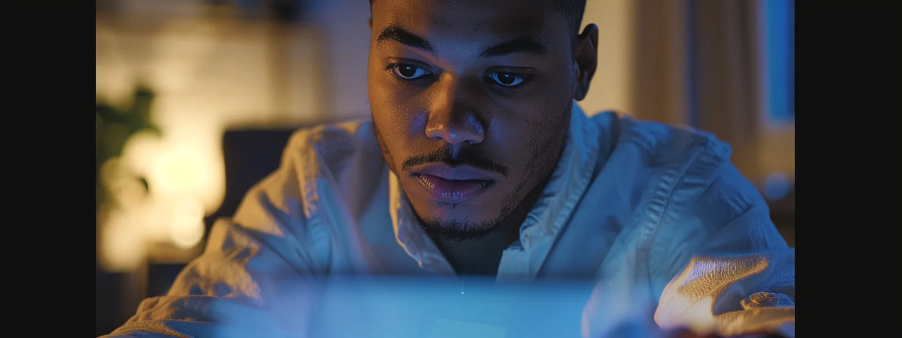 an individual typing on a computer while examining a suspicious email with a serious expression on their face.
